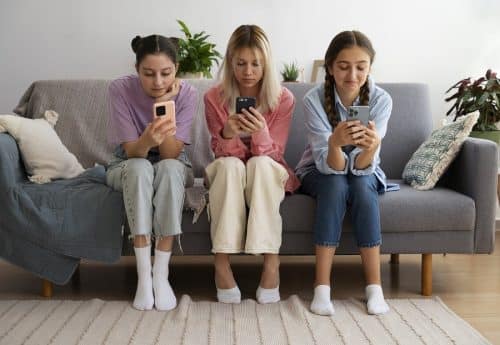 ragazze sedute sul divano con lo smartphone dipendenza